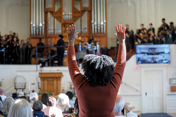 Woman standing, hands raised, in a BME concert in Union Church