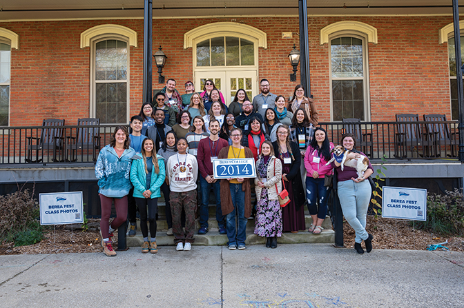 Members of the Class of 2014 stand on the steps of Fairchild holding their sign.