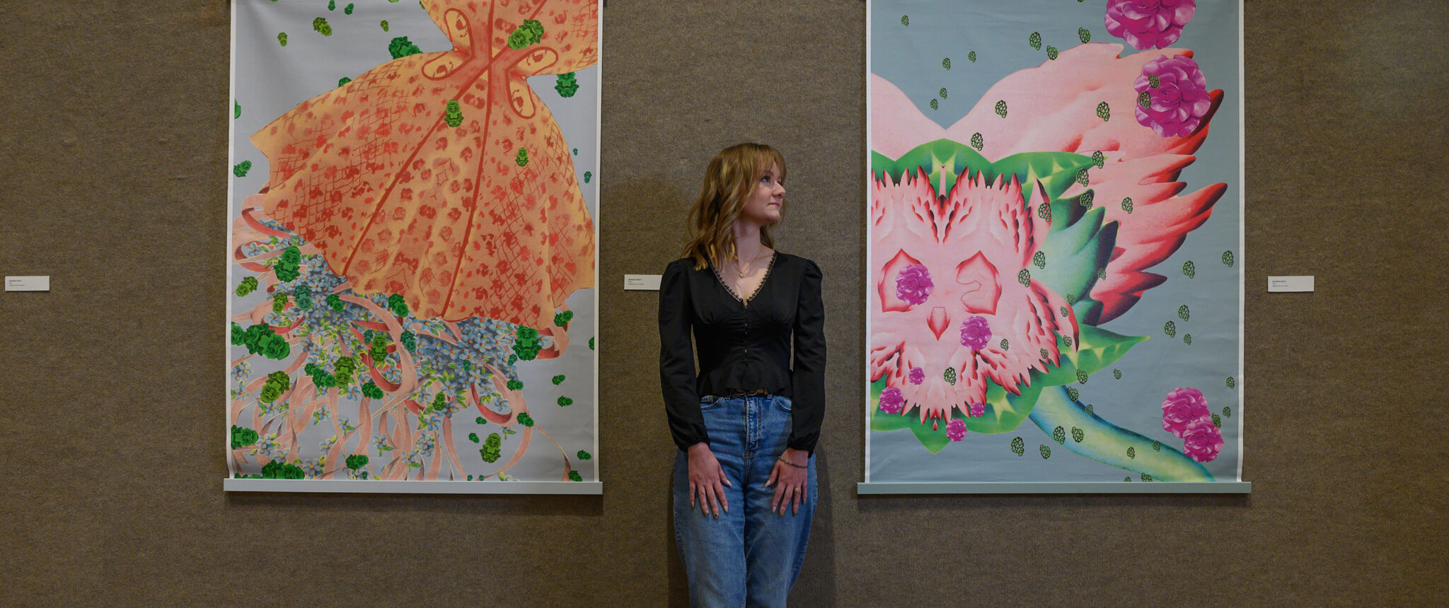 Student stands between two large colorful art pieces in the Doris Ulmann Galleries
