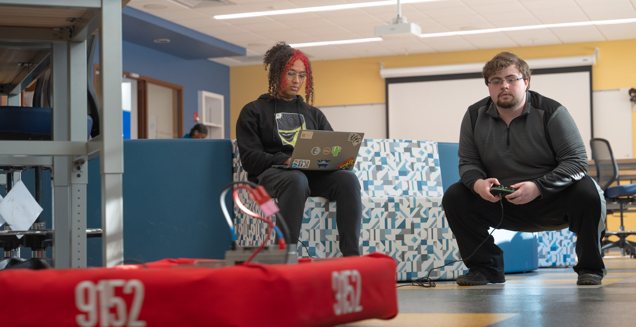 Two students sit in the new Makerspace in the CMIT technology building working on technology creations.