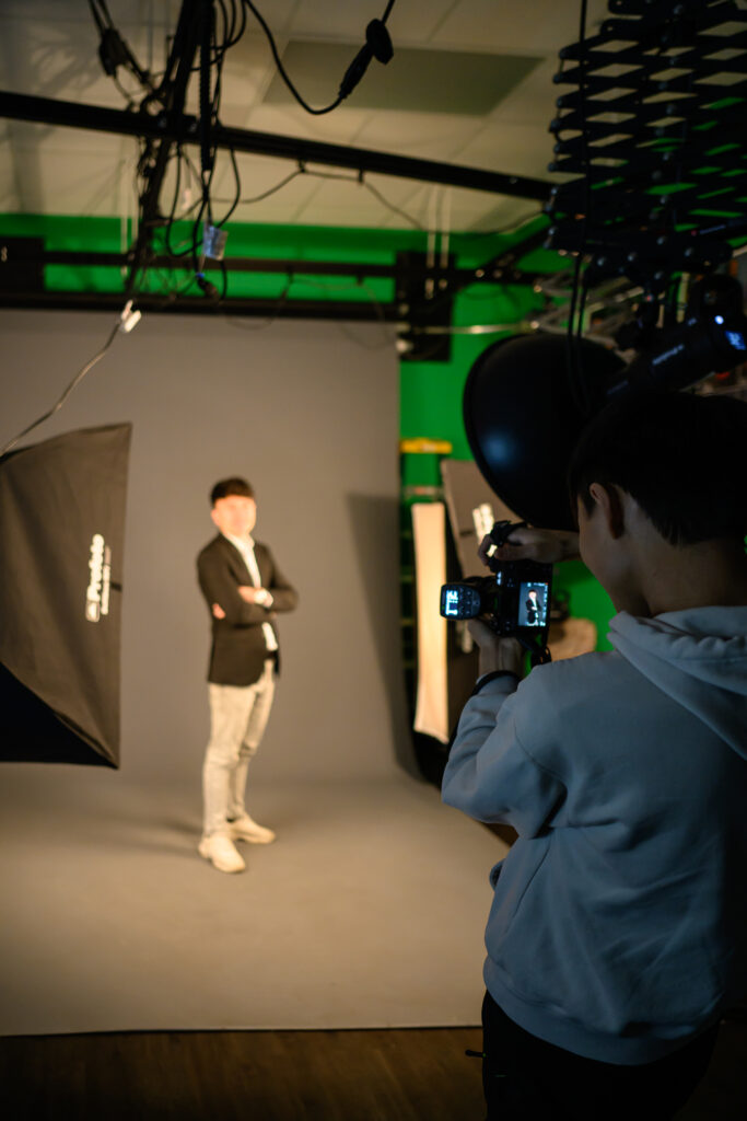 Feda '27 stand against a backdrop in the studio and a camera person is taking his photo
