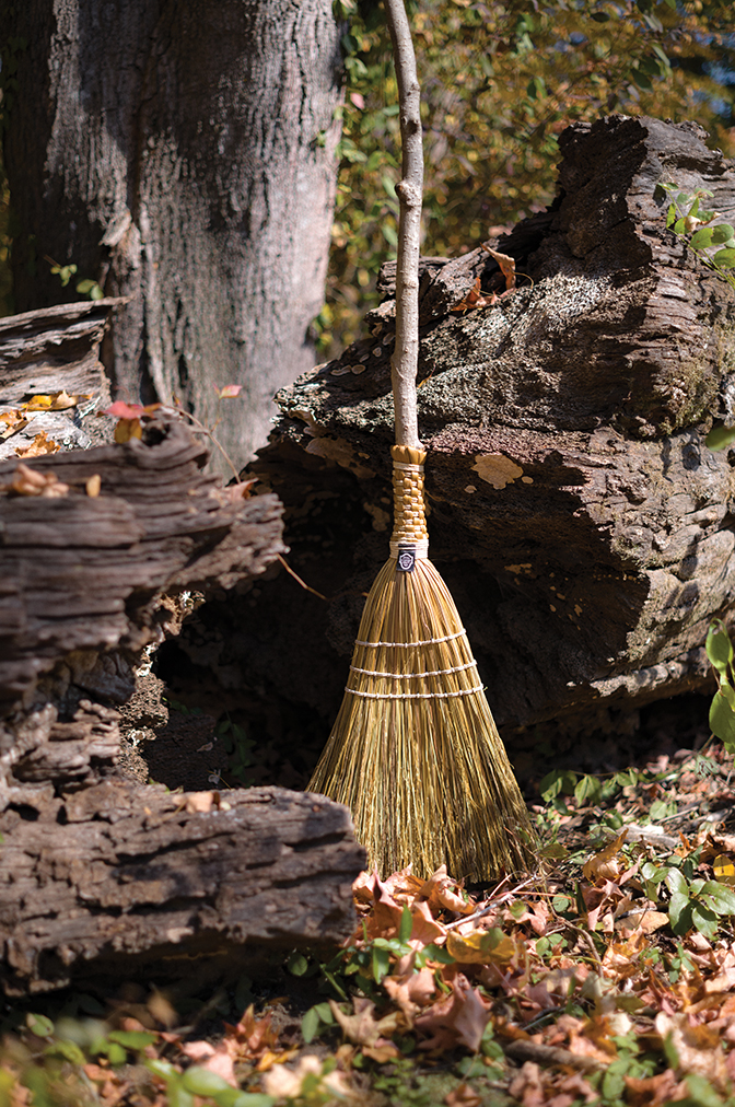 A Berea College broom leans against a rock in the forest.