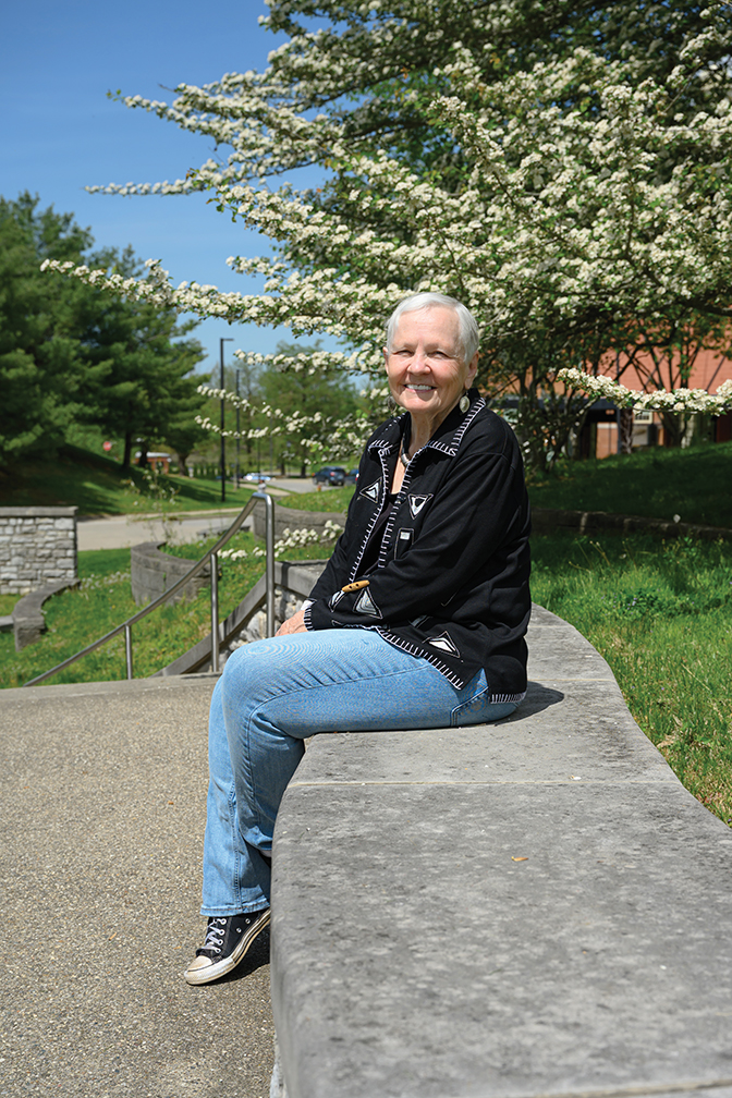 Dr. Bobby Starnes sits outside on campus. A dogwood tree is blooming in the background.