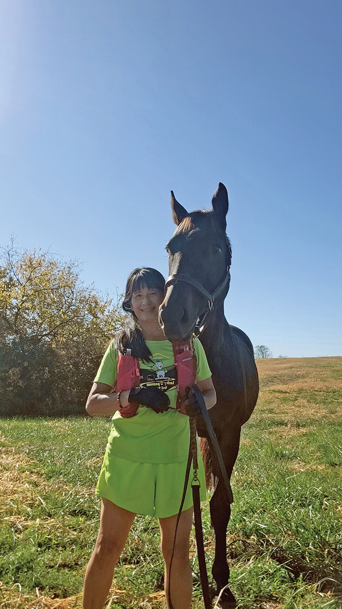 Penelope Wong stands beside a horse.