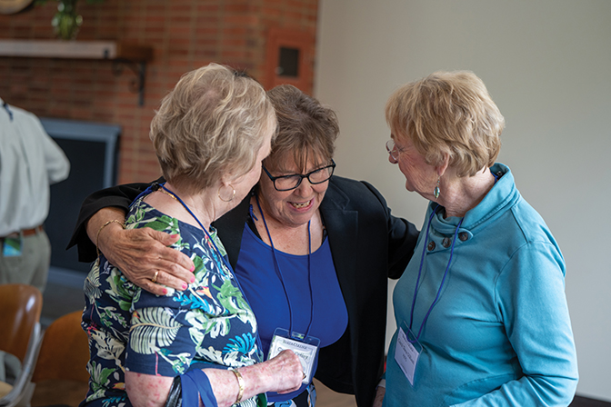 Group of three alumni women hug each other at the alumni awards ceremony