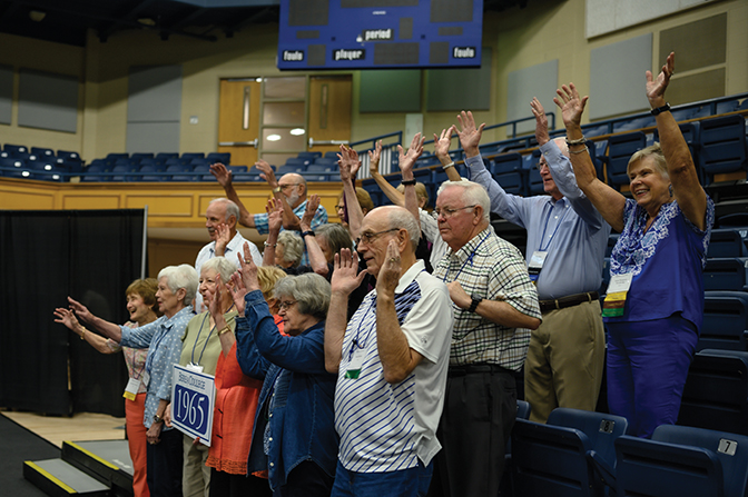 Members of the class of 1965 throw their hands up for a silly celebration pose during the indoor picnic.