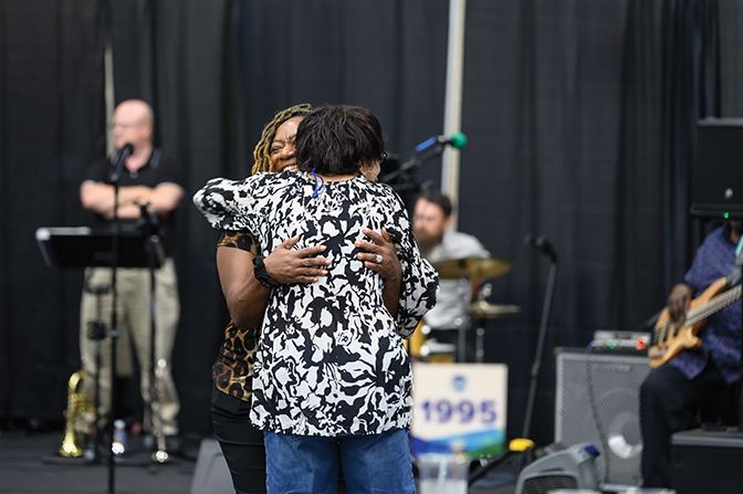 Two alumni embrace joyfully during the indoor picnic at Summer Reunion