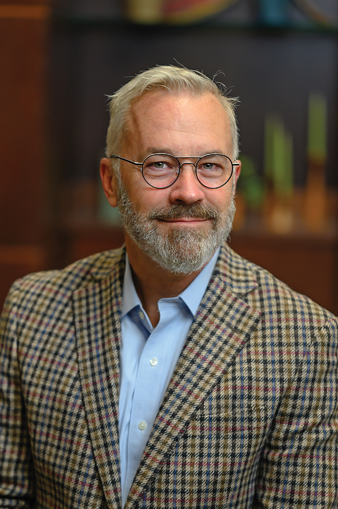 Chad Berry is wearing a blue shirt and a plaid jacket.