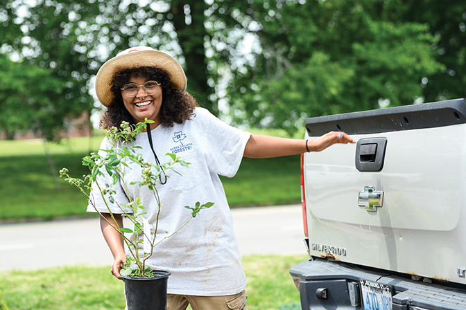 Autumn '28 holds a tree sapling she is preparing to plant at the Best-Evans house