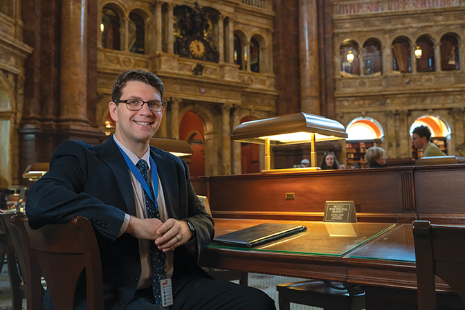 Sid Ferguson-English sits at a desk in the Library of Congress.