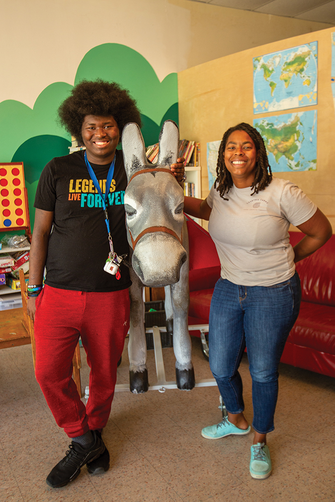 Student Anthony stands with apprentice, Jazmine LeBlanc next to a statue of a donkey.
