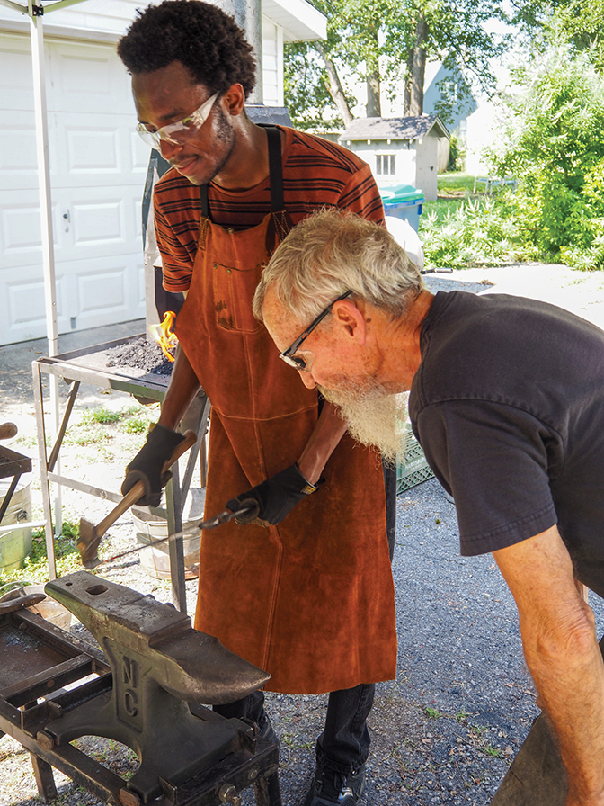 Student, Michael, pounds on a piece of metal during a blacksmithing lesson from mentor Bob Montgomery.