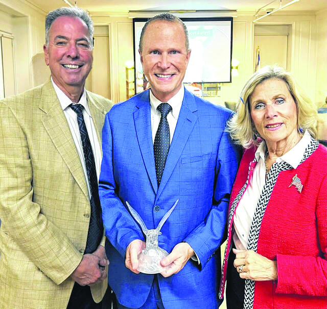 Photo of Gaitley Stevenson-Matthews standing with two other individuals, holding an award.