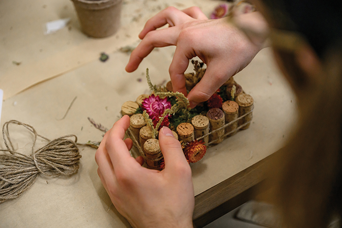 Up-close image of hands putting dried flowers into an art design