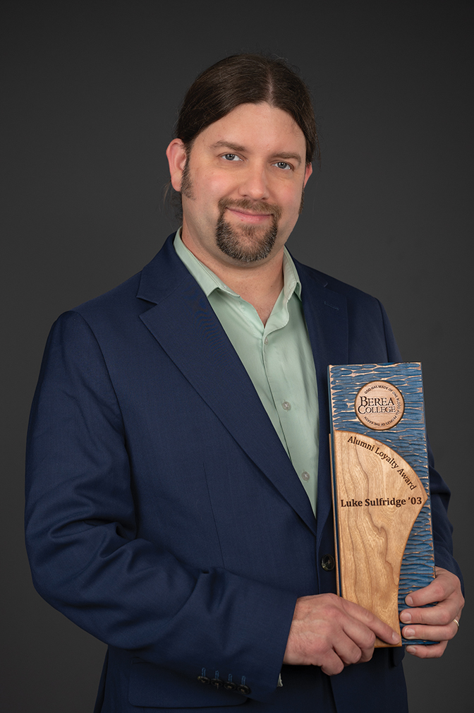 Portrait of Luke Sulfridge holding his alumni award.