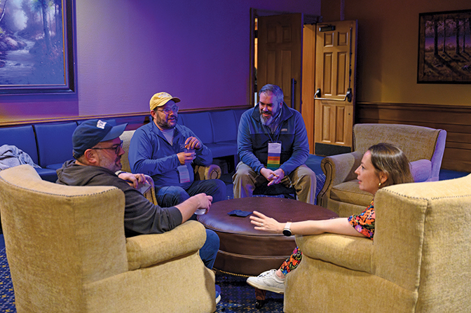 Four alumni sit in Boone Tavern in yellow chairs talking.