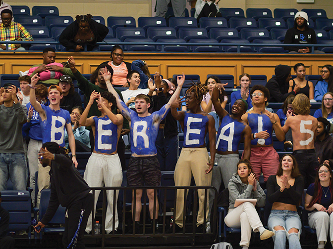 Five students with painted blue chests spell out the word BEREA during a basketball game.
