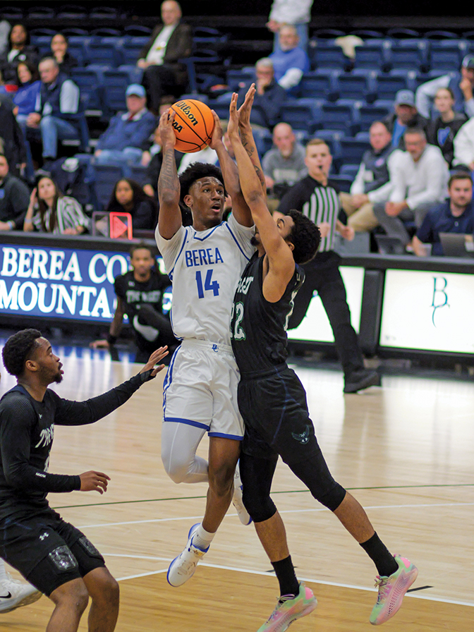Men's basketball player goes up for a shot over a defender.