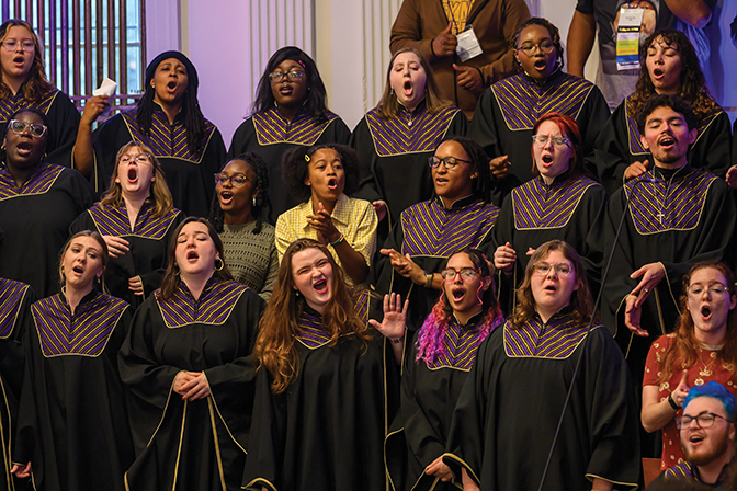 Group of Black Music Ensemble students dressed in black robes, joined by alumni, singing in Union Church.