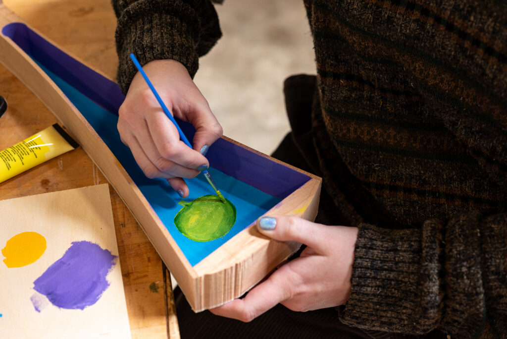 A student works on painting an instrument in Student Crafts.