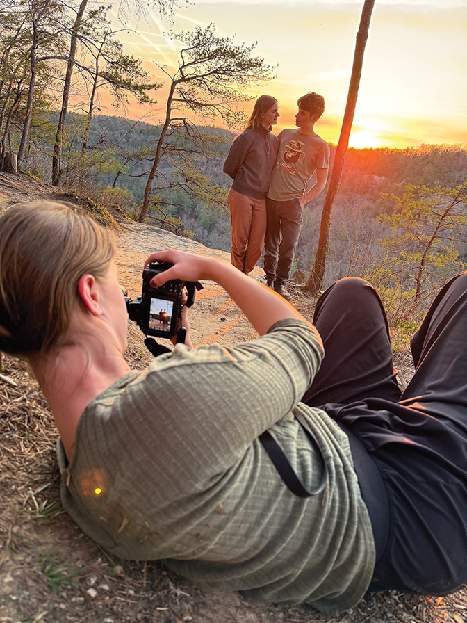 Kalilah '27 lays on the ground taking a picture of her brother and sister-in-law, Elijah Hicks and Moriah Wilbur. The sun set is in the background.