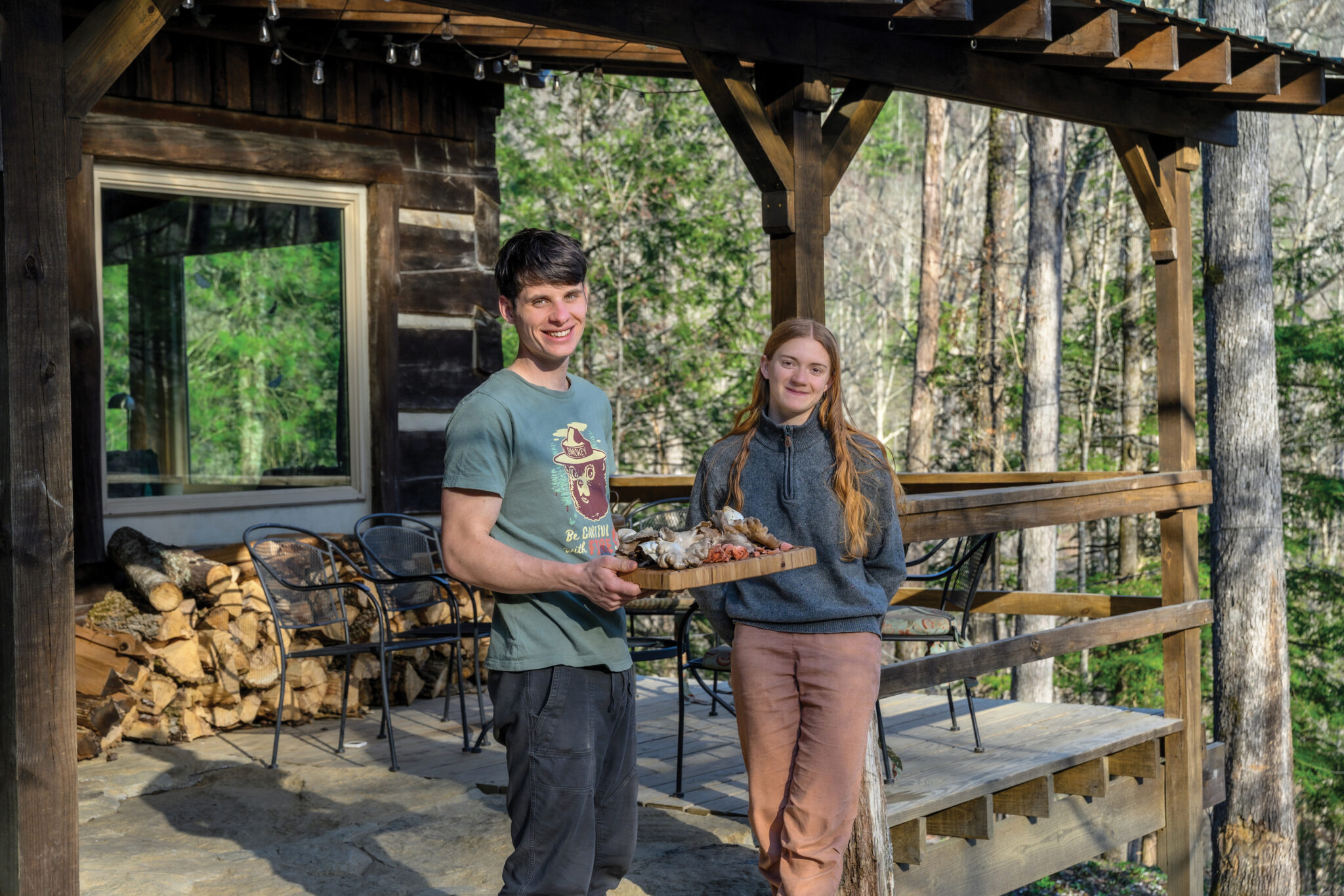 Portrait of Elijah Hicks and Moriah Wilbur holding a tray of mushrooms they grow on their farm.