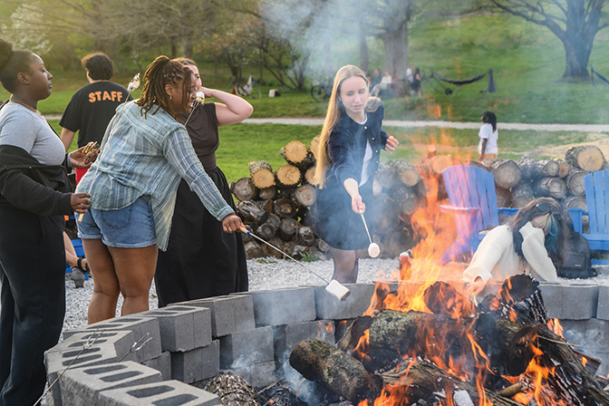 Students roasting marshmallows around a bonfire