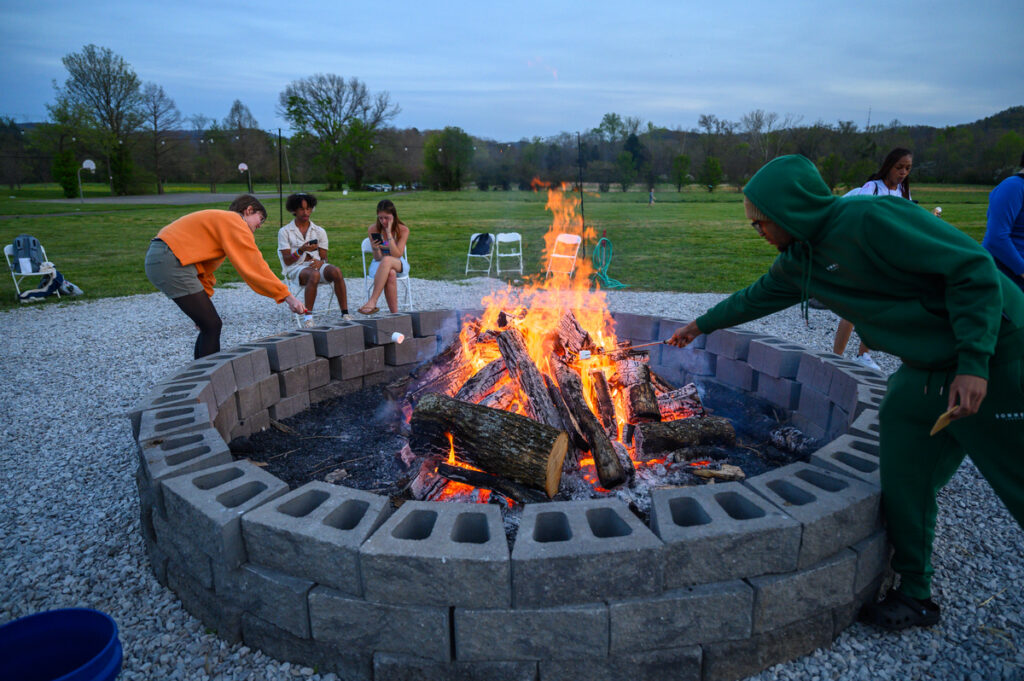 Students gathered around a large bonfire in the new fire pit at Alumni fields