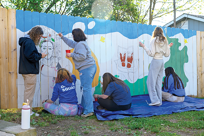 Students painting on a large mural