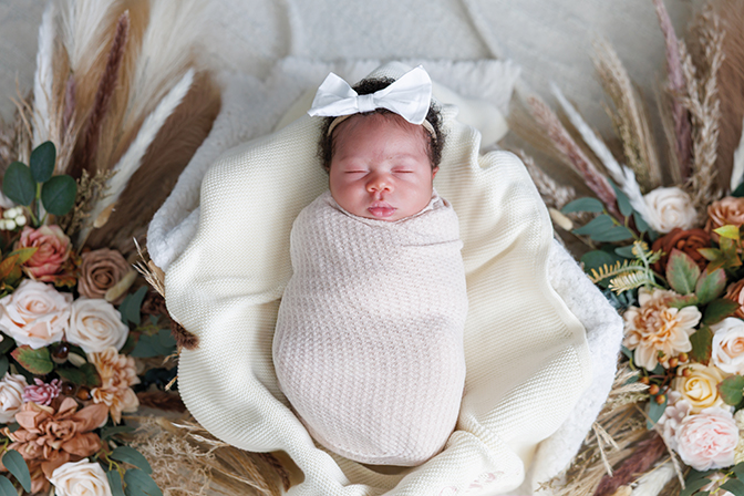 Portrait of a swaddled baby surrounded by flowers