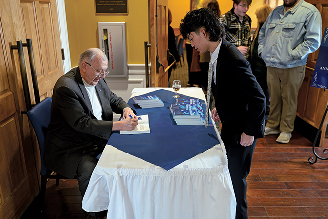 Donald W. Caudill '80 signs a copy of his book, "The Success Pyramid,"
for a Berea College student during the senior celebration for the business
department, which he has hosted annually for 26 years.