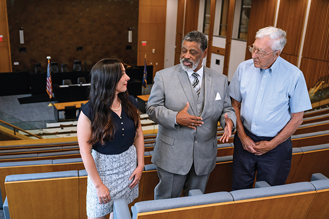 Emily Puckett '07, William Davis '74 and Robert Lawson '60 talk together in the grand courtroom at the University of Kentucky J. David Rosenberg College of Law in Lexington, Kentucky.
