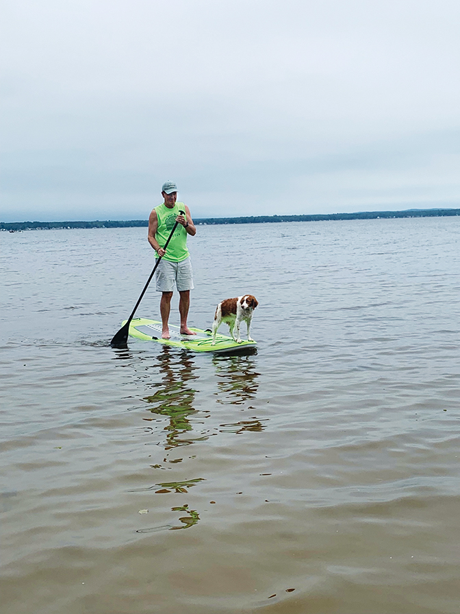 Dr. Lyle D. Roelofs Hon. '21 paddle boards with his dog. 